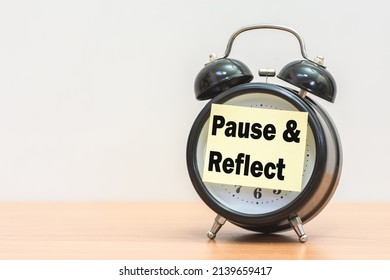 Written Pause  Reflect With Paper On Alarm Clock.
Pause And Reflect Word With Time Concept.