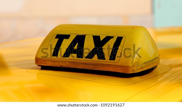 written yellow and\
black taxi above a car