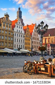 Wroclaw Central Market Square With Old Colourful Houses, Street Lamp And Walking Tourists People At Evening Sunset Sunshine.