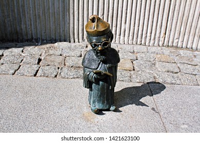 Wroclaw / Poland - 10/04/2018: Sculpture Of A Professor Dwarf, Standing In An Academic Dress And Reading A Book. Bronze Statue Of A Gnome - Symbol Of Wrocław.