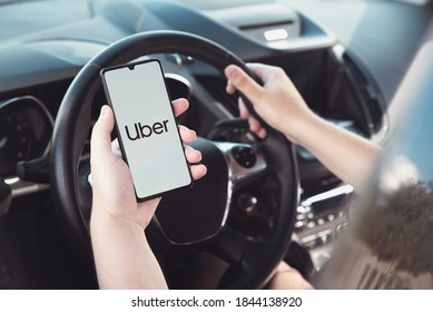 Wroclaw, Poland - AUG 25, 2020: Uber driver holding smartphone in car. Uber is sharing-economy service for ubran transport.