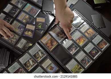 Wroclaw, Poland - February 25 2022: Browsing binders with a collection of magic the gathering cards - deck construction before friday night magic tournament with friends, top view