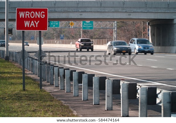 Wrong Way caution safety sign posted\
along a major interstate highway facing the opposite direction of\
traffic to avoid car vehicle collision\
accidents