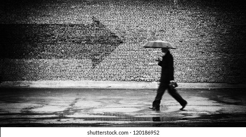 Wrong way. A man with umbrella. Conceptual image, film grain added - Powered by Shutterstock