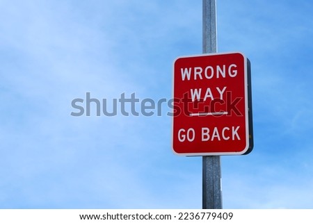 Wrong way sign against a blue sky