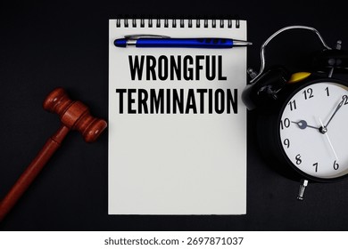 Wrongful Termination text written on notepad with gavel and alarm clock on black background
