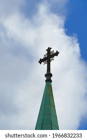 Wrought Iron Cross On Church Spire With Dramatic Clouds In Background