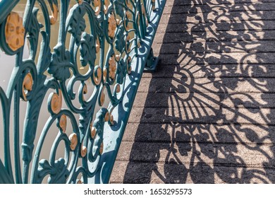 Wrought iron decorative fence on bridge. Forming an interesting design with it's cast shadow on the floor. Selective focus.