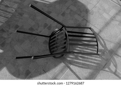 Wrought Iron Garden Chair Creating Shadows Upon Shadows On Patio Tiles.