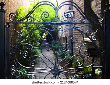 Wrought iron gate doorway entrance to sunlit sidewalk pathway at a house residence.