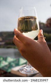 Wurzburg, Germany 2020: Women Holding White Wine Glass With Ring On Her Thumb. In The Wine You Can See The Marienberg Fortress Upside Down.