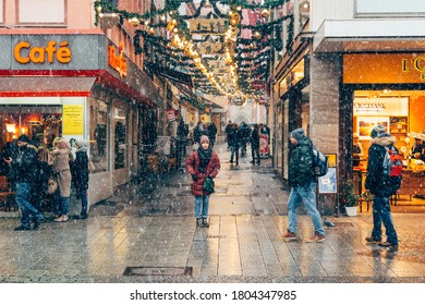 Wurzburg/Germany-3/1/19: An Alone Woman Standing On Schustergasse, On A Snowy Winter Day, In The Centre Of Wurzburg, Brightly Decorated For Christmas