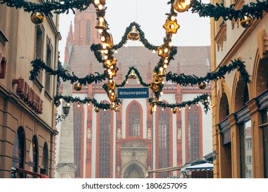 Wurzburg/Germany-3/1/19: Schustergasse Street Name Sign Between The Bright Christmas Decorations Placed On The Streets Of The City During The Holidays