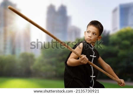Wushu practice outdoors. Young fighter with a stick in his hands