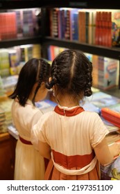 Wuxi, China, June-2022: Two Little Asian Girls In China Ancient Style Dress Reading Books In A Book Store. 