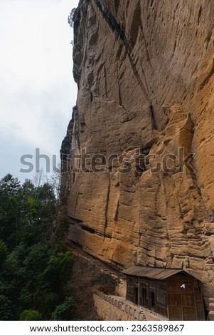 Wuyishan mountains in Fujian Province, China. Temple On the path to DaWang (Great King) Peak. View over the mountains with a steep cliff and trees in the foreground. Wuyishan is a UNESCO site in China