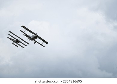 WW1 biplane and triplane fighter aircraft in simulated dogfight over airfield in Cambridgeshire, England on overcast day.