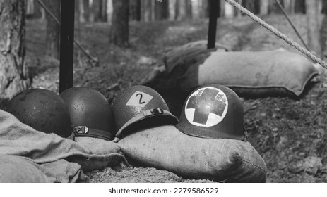 WWII American Metal Helmets Of United States Army Infantry Soldier At World War II. Helmets Near Camping Tent In Forest Camp. Black And White Colors.