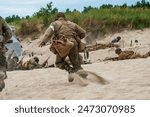 WWII  Historical reconstruction. An American medic during a battle on the beach. View from the back.