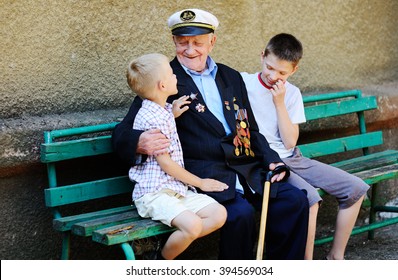 WWII Veteran With Children. Grandchildren Looking At Grandfather's Military Awards.