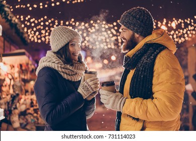 X Mas Time! Cute Married Family Is Having A Walk In Park On A Cold Night, Enjoying Tea, Dressed Warm In Head Wear, Gloves, Scarves, Looking At Each Other, Chatting, Laughing