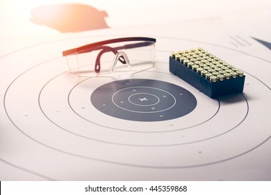 x on paper target with safety glasses and 9 mm bullet with flare and vintage color focus on 'x'