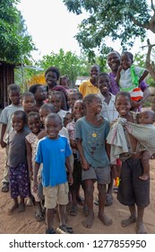 Xai Xai, Mozambique, April, 2014: Young Children And Male Adult Keen To Have Their Portraits Made In The Poor Village - Portrait Format Showing Footwear And Mismatch Clothing