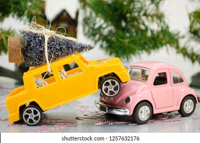 XALAPA, VERACRUZ, MEXICO- DECEMBER 6, 2018: Toy Car Accident. Yellow Car Carrying A Christmas Tree On Top Of A Pink Car On A Car Crash, With Pine Trees And A A Little House Out Of Focus