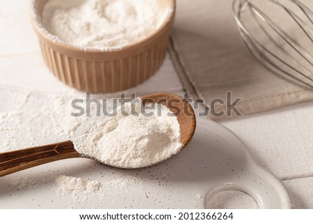 xanthan gum food additive for dough on white plate in wooden spoon with metal whisk