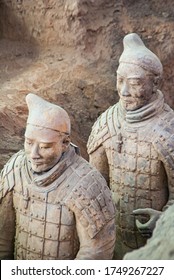 Xian, China - May 1, 2010: Terracotta Army excavation site. Closeup of 2 Beige-gray sculpture of soldiers standing in line behind each other in a trench.