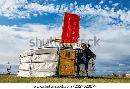 Xilinhot, Inner MongoliaChina - 07 20 2017: Girl with cow boy hat standing in front of a tent in inner Mongolia in China. Wind waves the flag above the yurt. 
