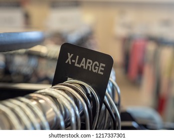 X-large extra large clothes section sign on steel hanging rack with hangers in a department store