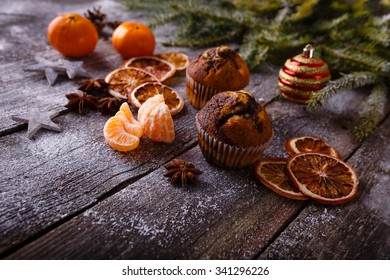 Xmas composition with holiday decoration - Homemade christmas cupcakes, sliced dried oranges and mandarin on wooden background with spruce twigs and christmas toy. Christmas card. Space for text
