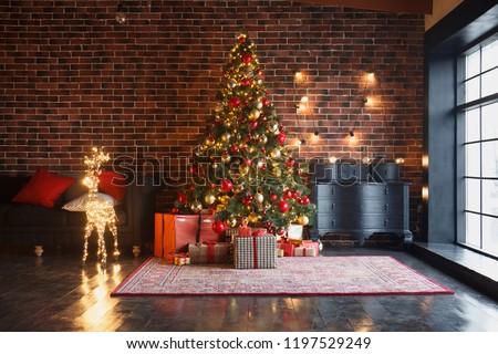 Xmas, New Year interior with red brick wall background, decorated fir tree with garlands and balls, dark drawer and deer figure