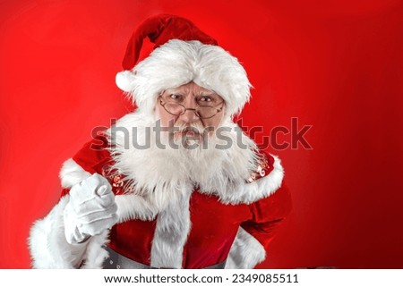 Xmas Santa Claus with fig sign obscene gesture. Emotional senior male model old man with a natural white beard Father Christmas. Joyful character for advertising