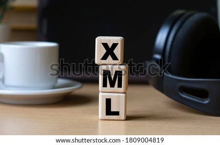 XML -acronum on cubes on the background of the tablet, headphones and a white cup. Technology and computers concept.