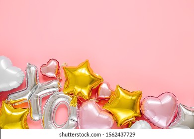 XO foil balloon letters and air balloons of heart shaped and stars. Holiday and celebration. Valentine's Day or wedding/bachelorette party decoration. Colorful Metallic air balloons on pink background