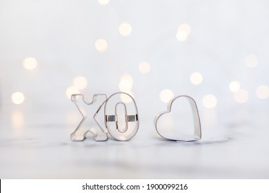 XO And Heart Cookie Cutters On White Background With Twinkle Lights