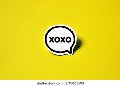 xoxo speech bubble on white paper isolated on yellow paper background with drop shadow. COPY SPACE.