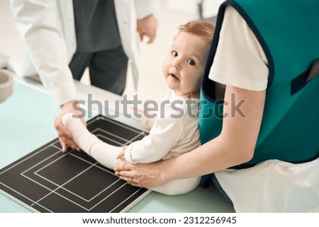 X-ray technician preparing small child for lower limb radiography