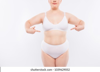 Xxl Fatty Chubby Model Wearing White Lingerie Is Demonstrating Her Flabby Stomach With Fat Folds, Sagged Skin, Scars And Stretch Marks, Isolated On White Background