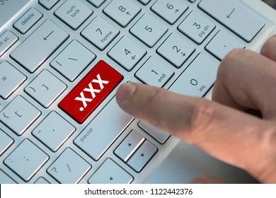  XXX button on keyboard. A male finger presses a color button on a gray silver keyboard a modern laptop. Button with inscription close up. Watching pornography on a computer. Internet Masturbation.