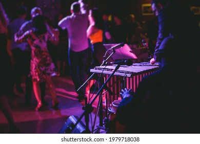 Xylophone Concert View Of Vibraphone Marimba Player, Mallets Drum Sticks, With A Latin Orchestra Musical Band Performing In The Background