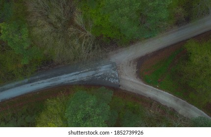 Y Shaped Crossroads Visible From Above. Green Trees And Grey Road With Transition From Asphalt To Gravel.