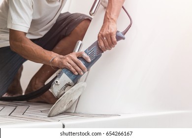 Yacht maintenance. A man polishing side of the white boat by grinder machine in the marina - Shutterstock ID 654266167