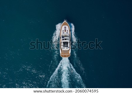 Yacht movement on blue water top view. Luxury yacht on the water aerial view. White yacht fast movement on the water top view. Travel - image. Top view of a white high-speed boat.