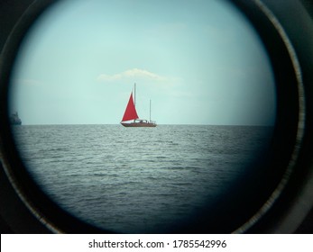 Yacht with a red sail on the high seas. A sailboat floats in the ocean near the shore. A boat with a sail on the waves of a calm sea. Telescope view - Shutterstock ID 1785542996