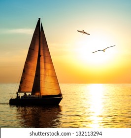 Yacht sailing against sunset. Holiday lifestyle landscape with skyline sailboat and two seagull. Yachting tourism - maritime evening walk. Romantic trip on luxury yacht during the sea sunset.