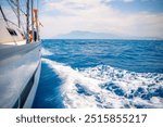 Yacht sailing in an open sea. Close-up view of side of the boat. Clear sky after the rain, waves and water splashes. High quality photo