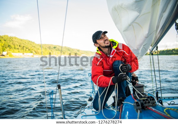 Yacht\
sailor pulling rope. Man working on\
sailboat.